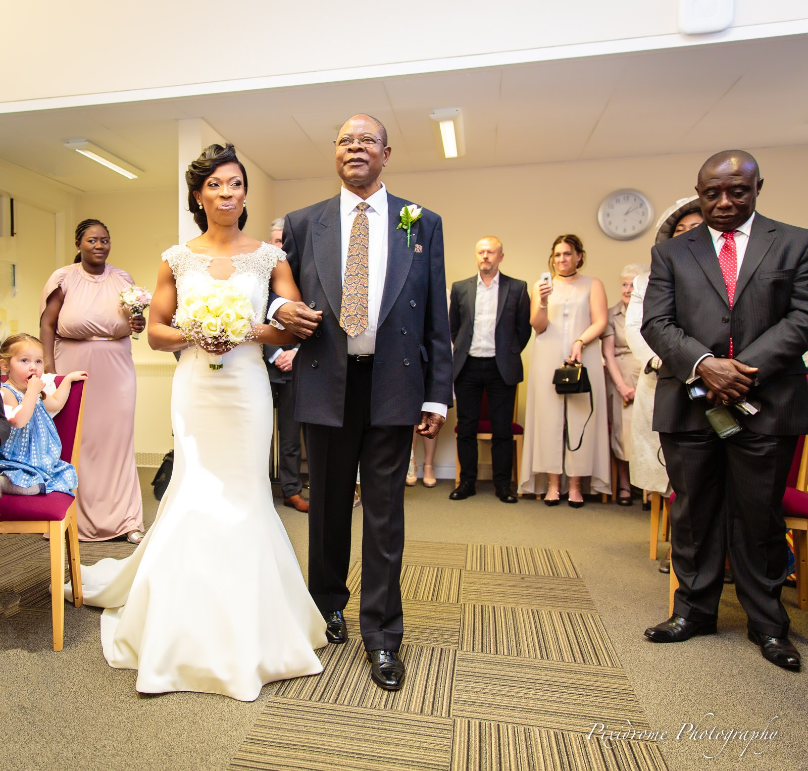 The bride walking down the aisle on her father's arm as guests stand