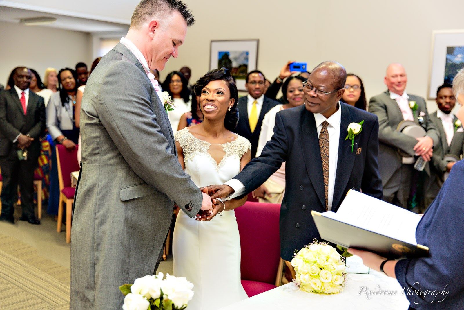Bride and groom holding hands before the registrar during the ceremony