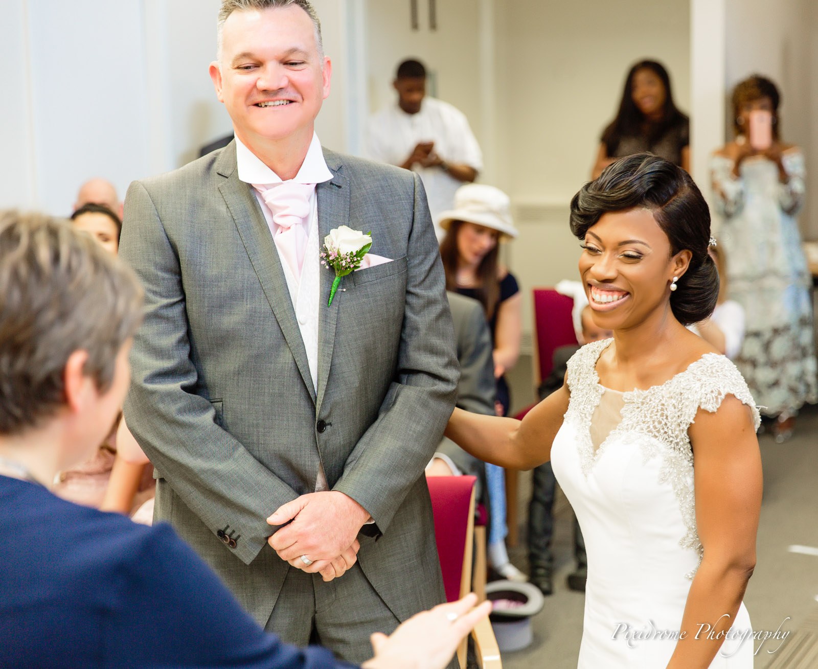 The bride resting a hand on the groom's shoulder at the ceremony, both smiling