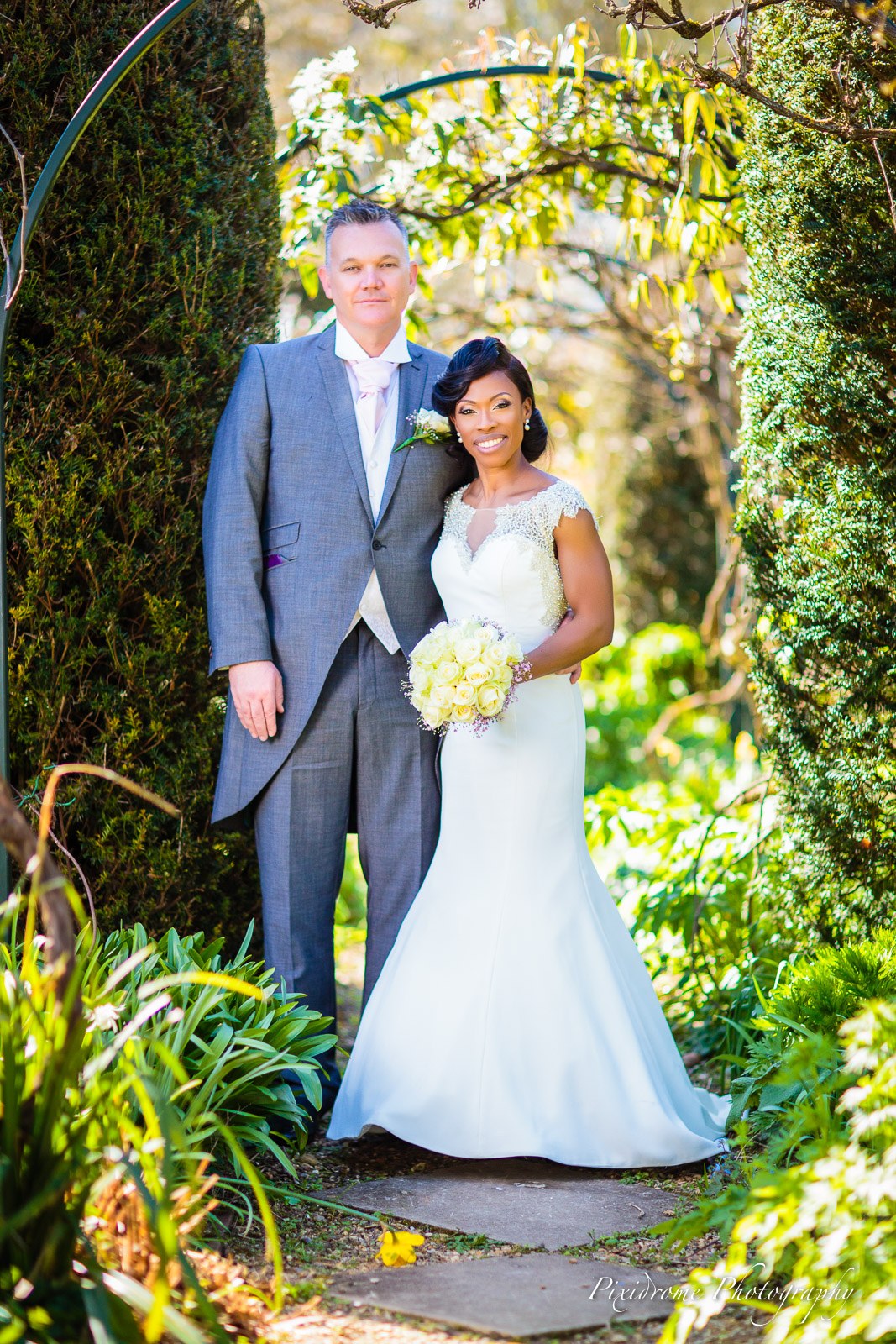 The couple beneath a leafy garden arch in the gardens of Chenies Manor House