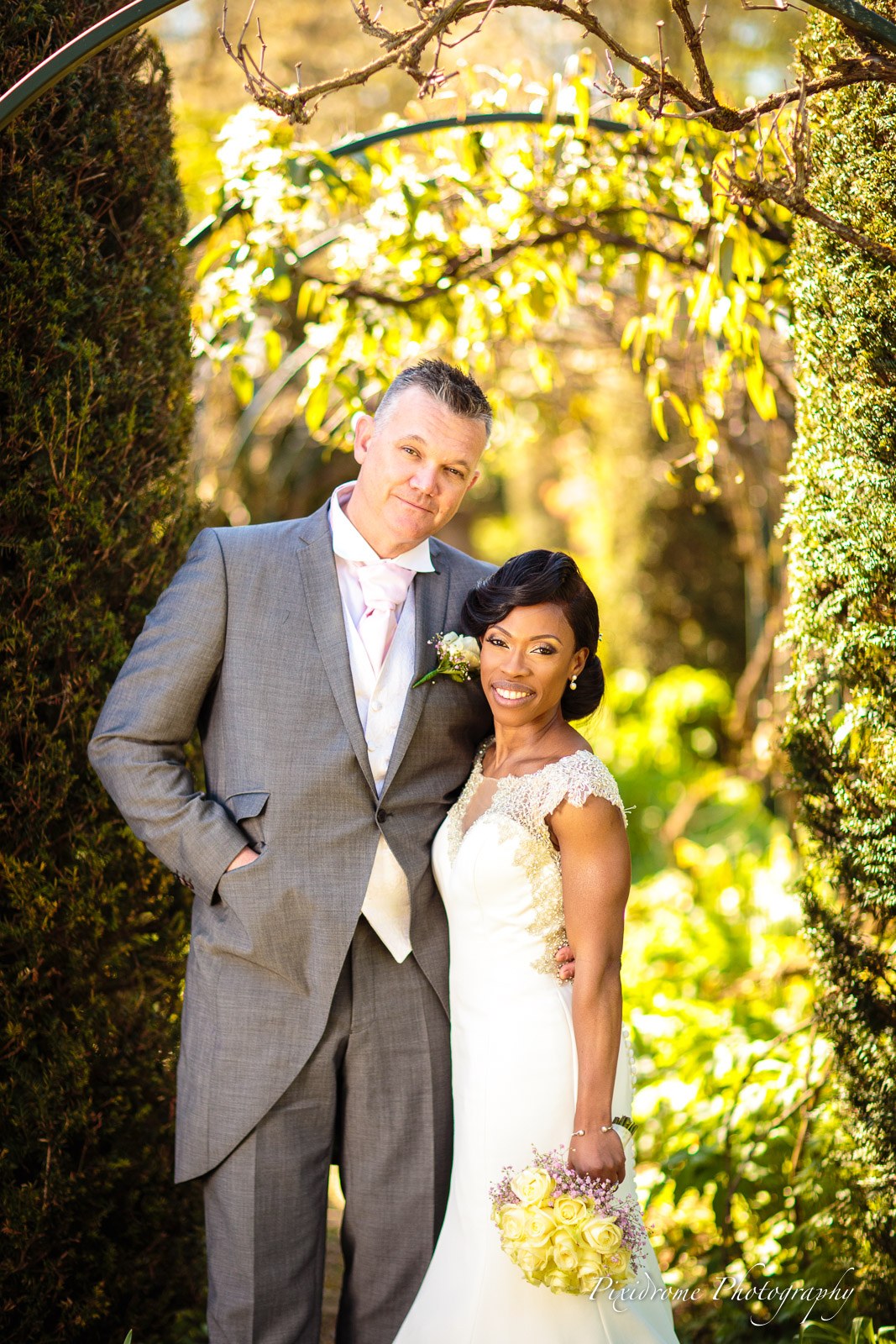 The couple framed by a blossoming garden archway at Chenies Manor House