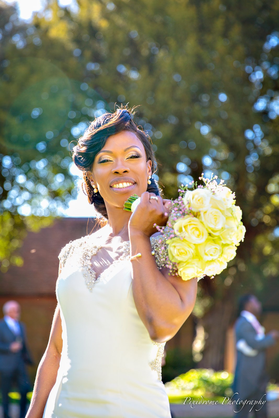 The bride holding up her yellow rose bouquet with a broad smile