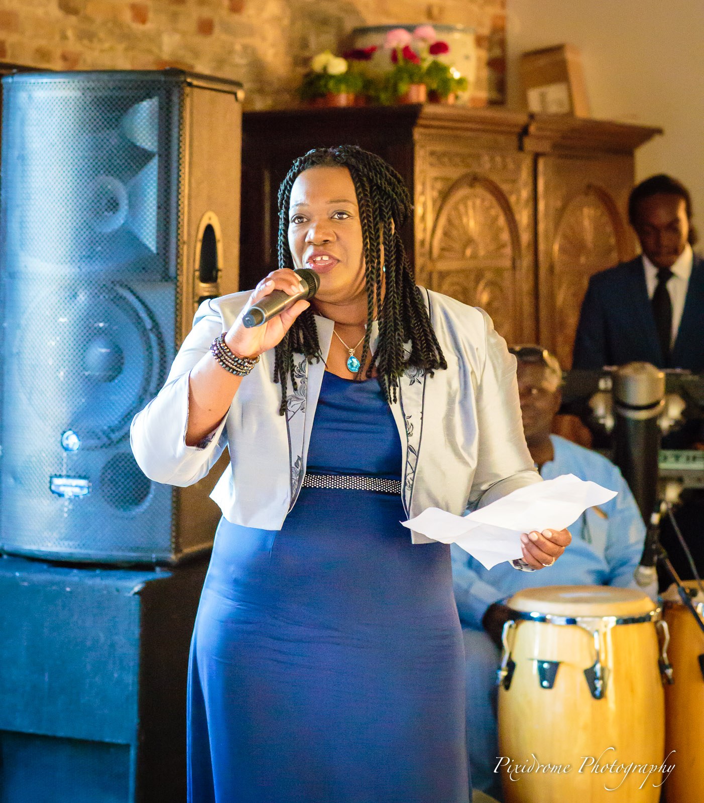 A woman holding a microphone and notes with the band behind