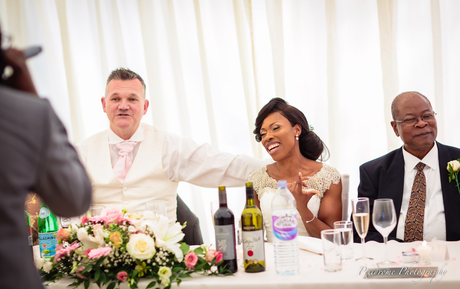 The bride laughing at the top table between the groom and her father