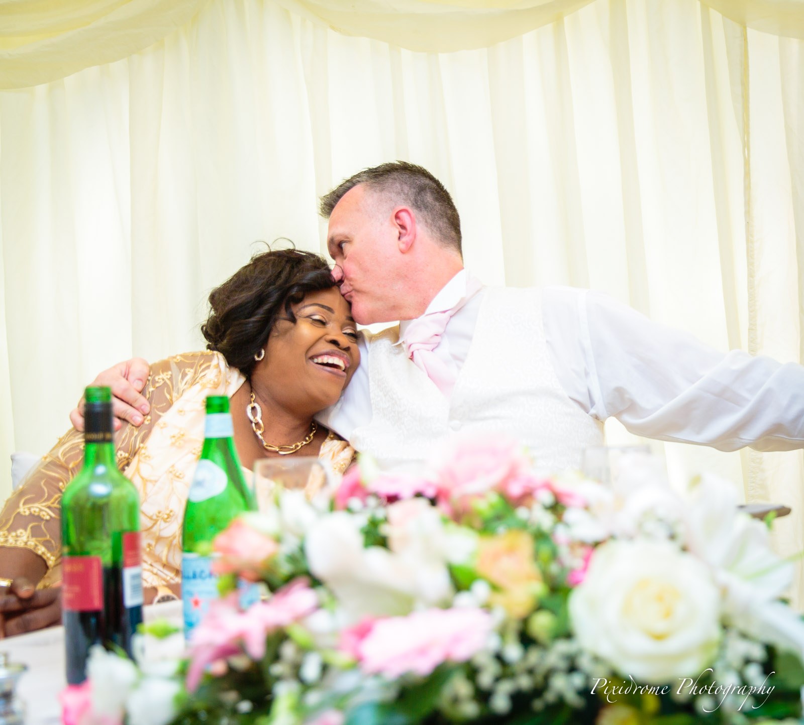 The groom kissing the mother of the bride on the head at the top table