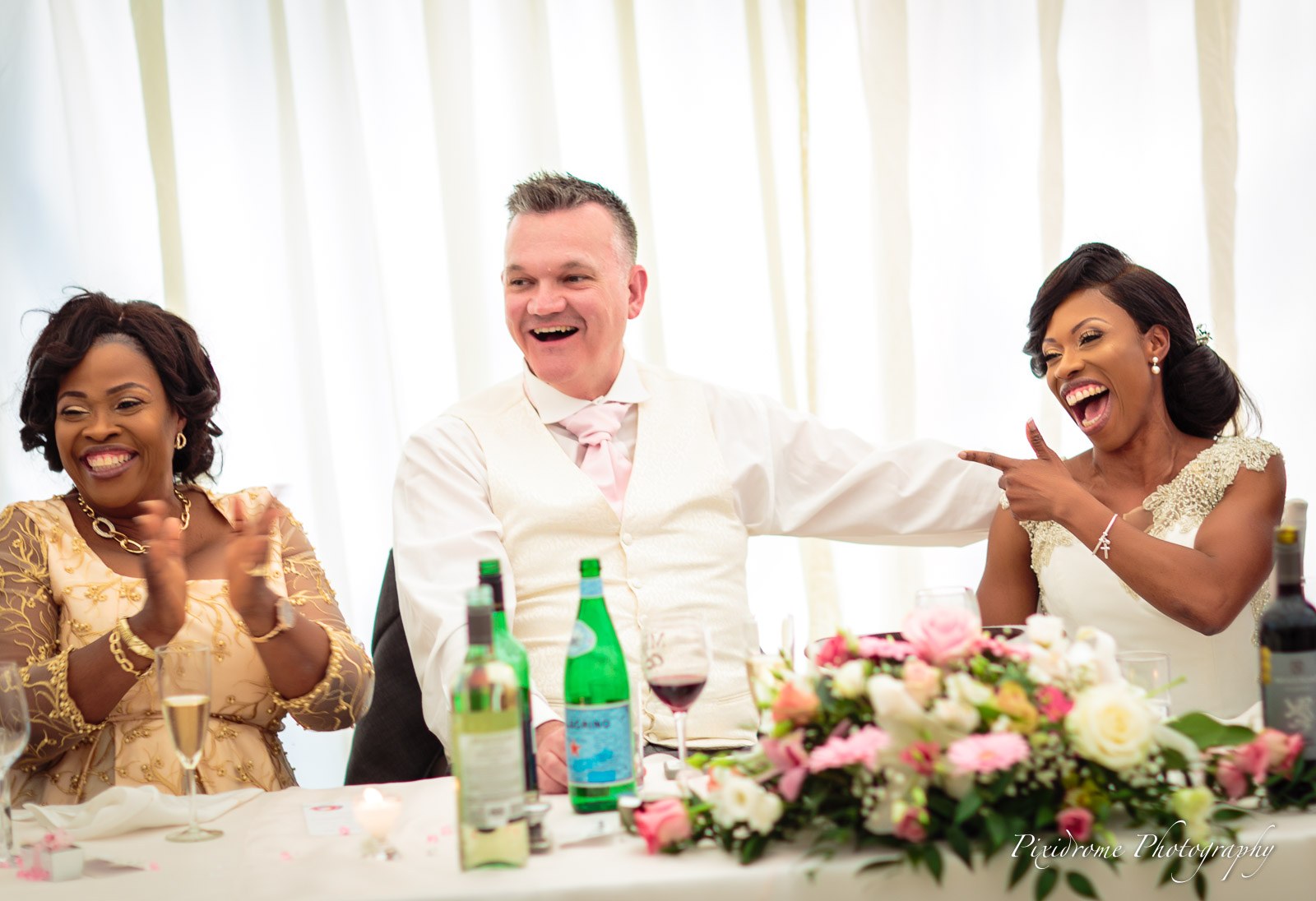 The bride laughing and pointing at the groom during the speeches