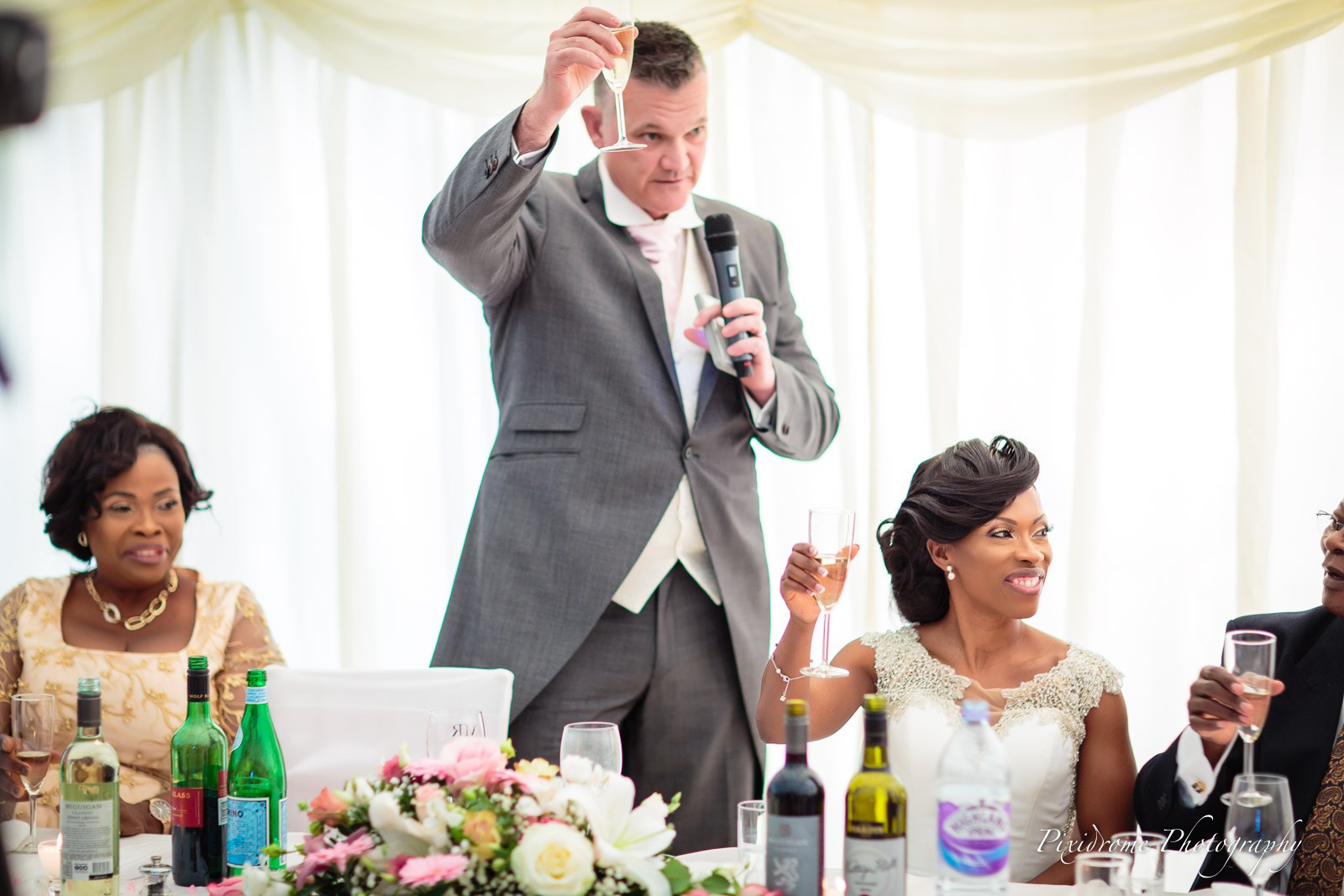 The groom raising a toast with the bride beside him