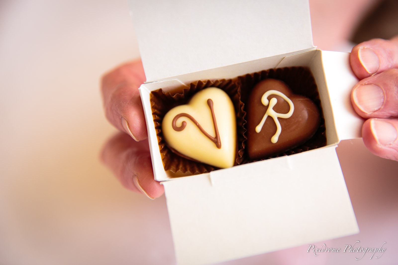 Close-up of two heart-shaped chocolates piped with the couple's initials