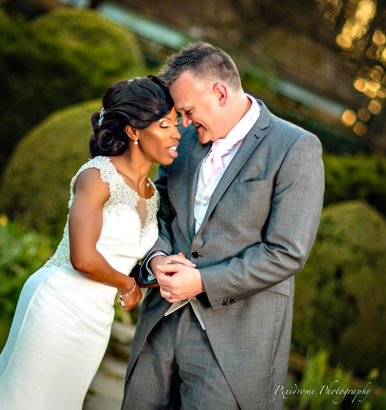 A close portrait of the couple, foreheads together, in the gardens of Chenies Manor House