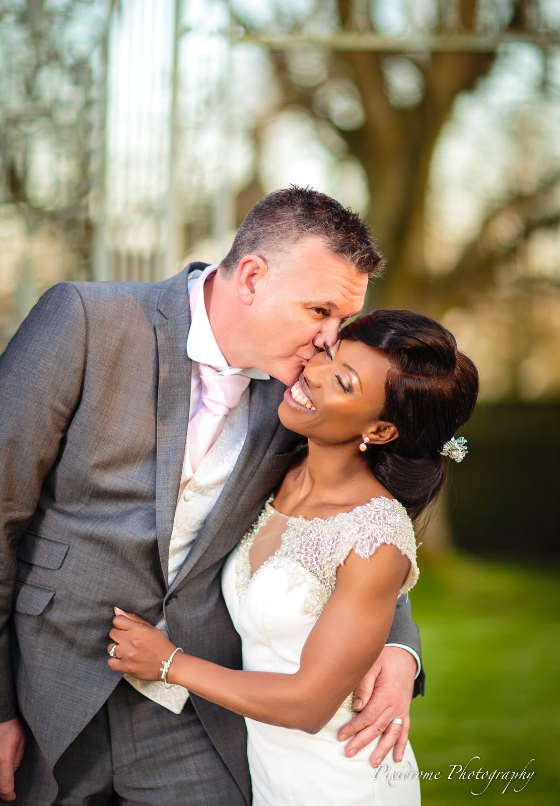 The groom kissing the bride's forehead in golden evening light