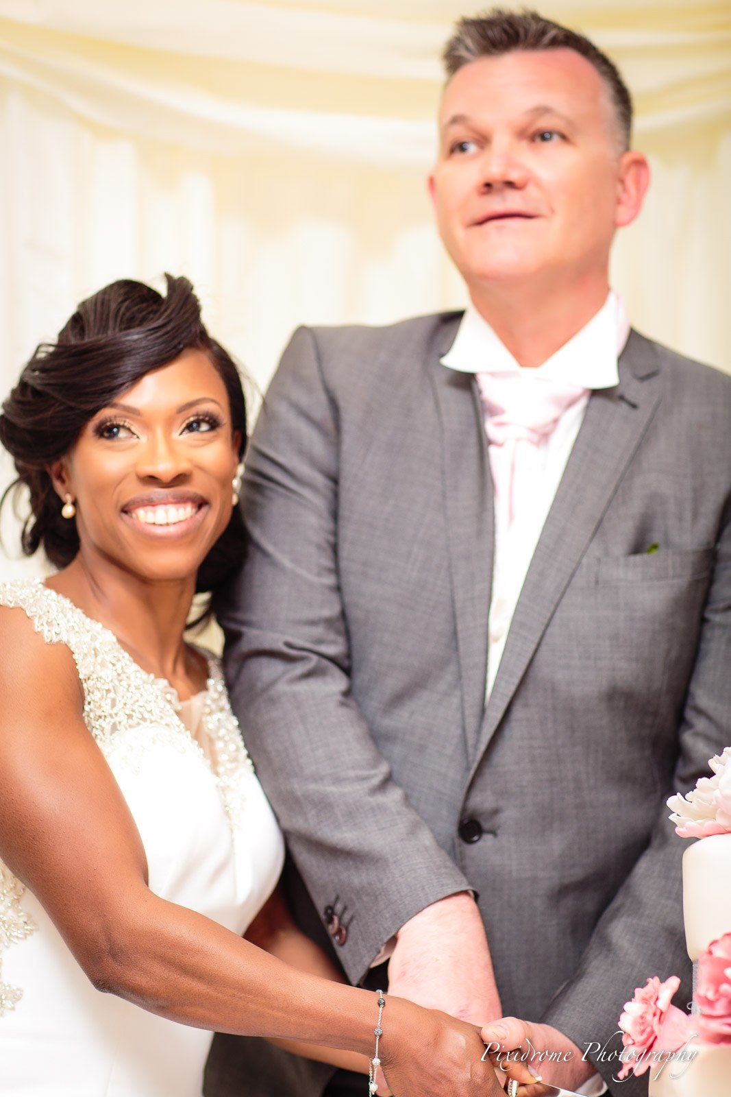 The couple standing together beside their wedding cake