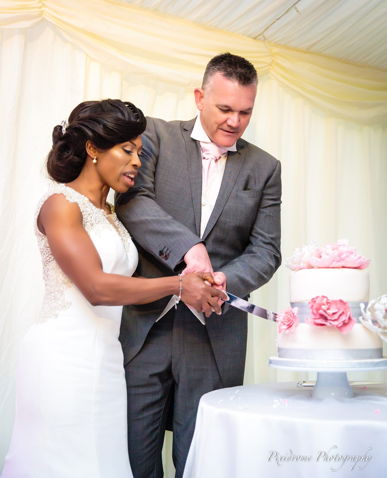 Bride and groom cutting the cake together in the marquee at Chenies Manor House