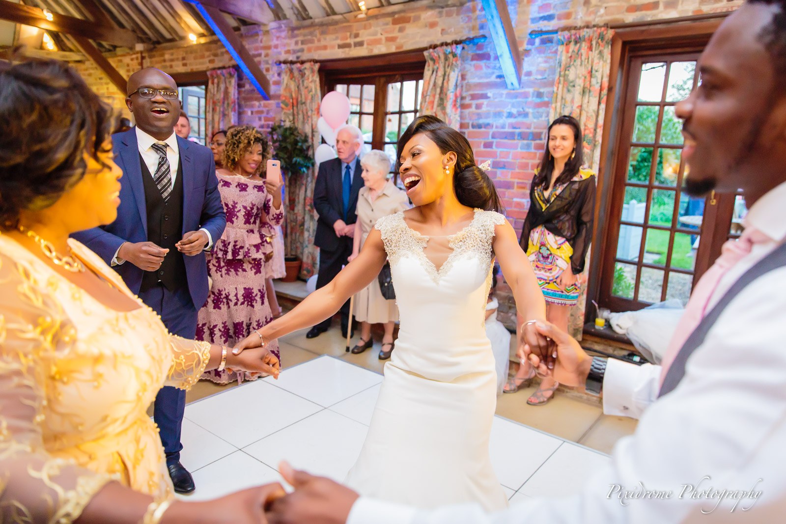 The bride dancing hand in hand with guests in the beamed hall