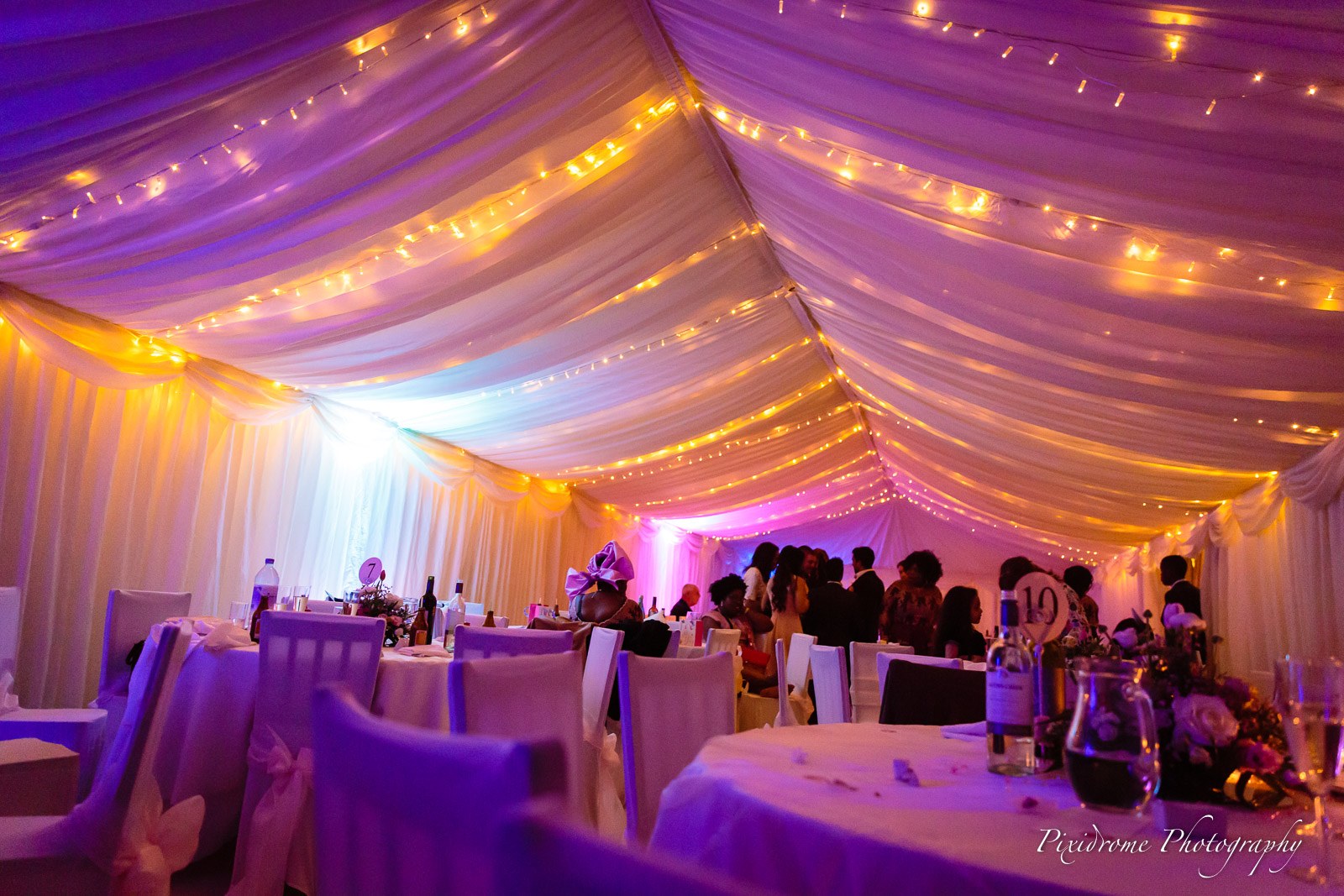 The marquee at Chenies Manor House glowing purple at night with festoon lights