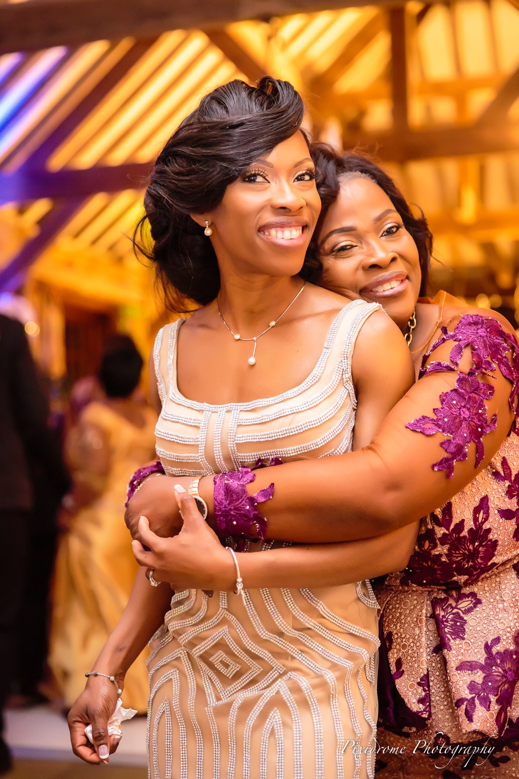 The bride cheek to cheek with a guest in warm evening light