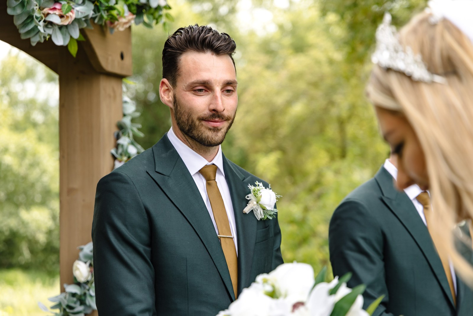 The groom smiling at the ceremony, the bride's tiara in the foreground