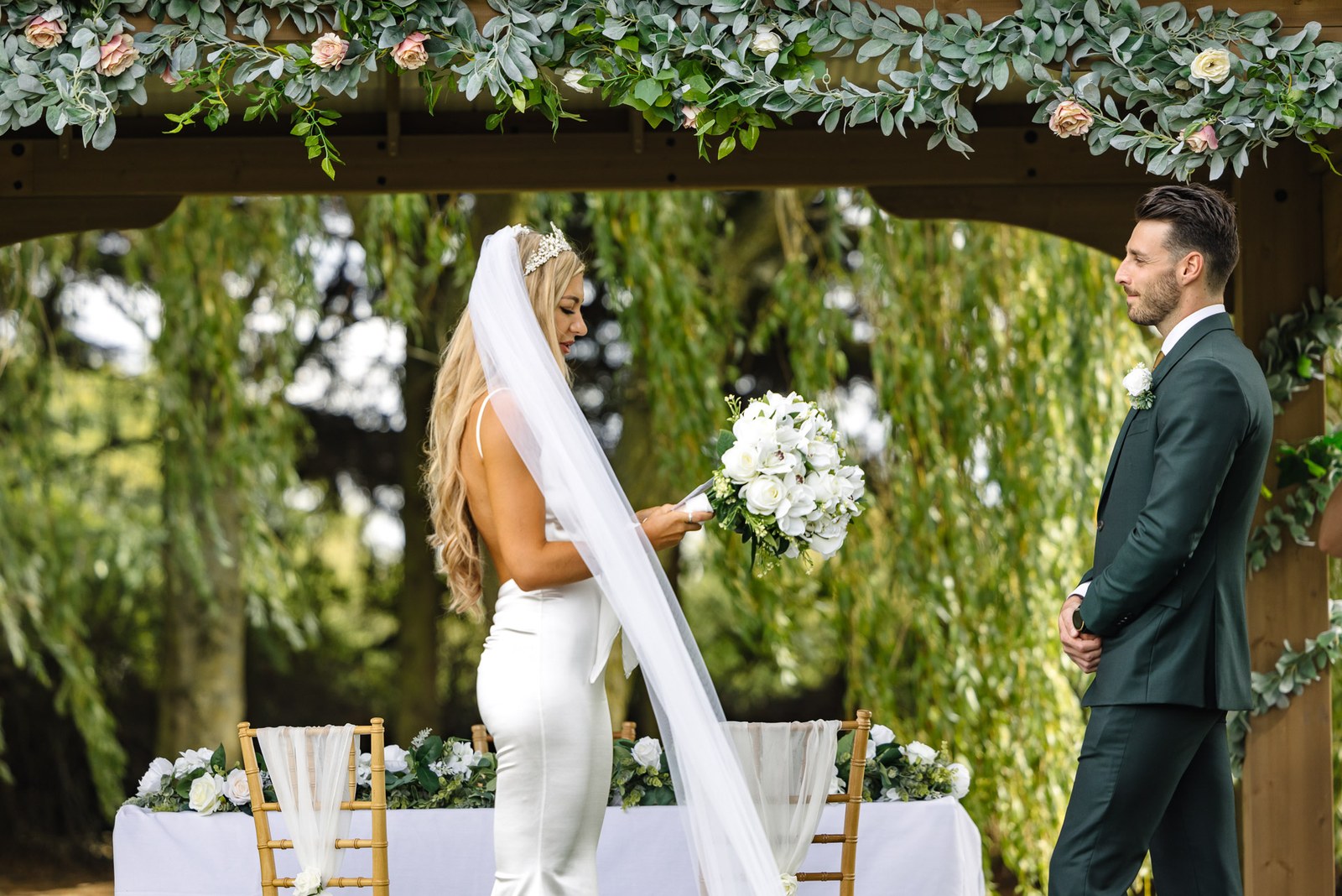 The couple beneath the foliage arch during their vows