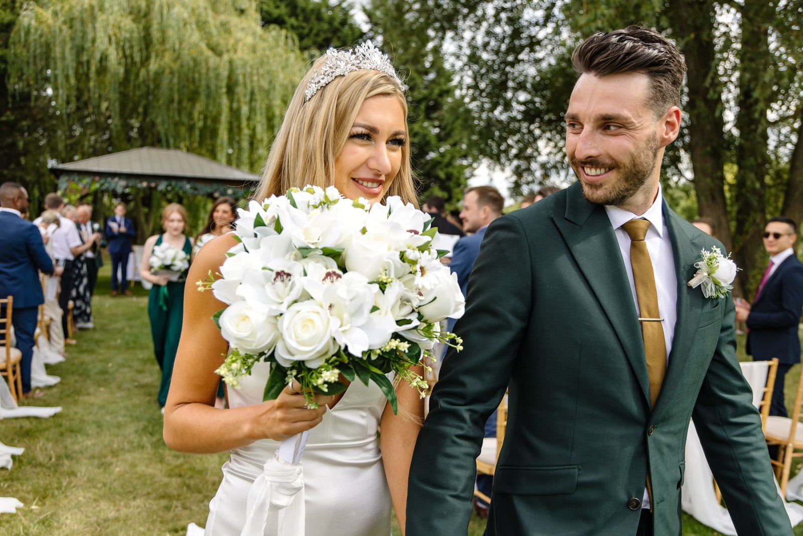 The newlyweds coming up the aisle, the bride's large white bouquet held high