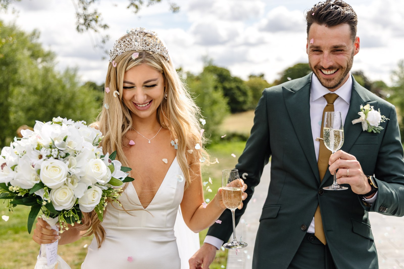 The couple walking with champagne as confetti falls around them