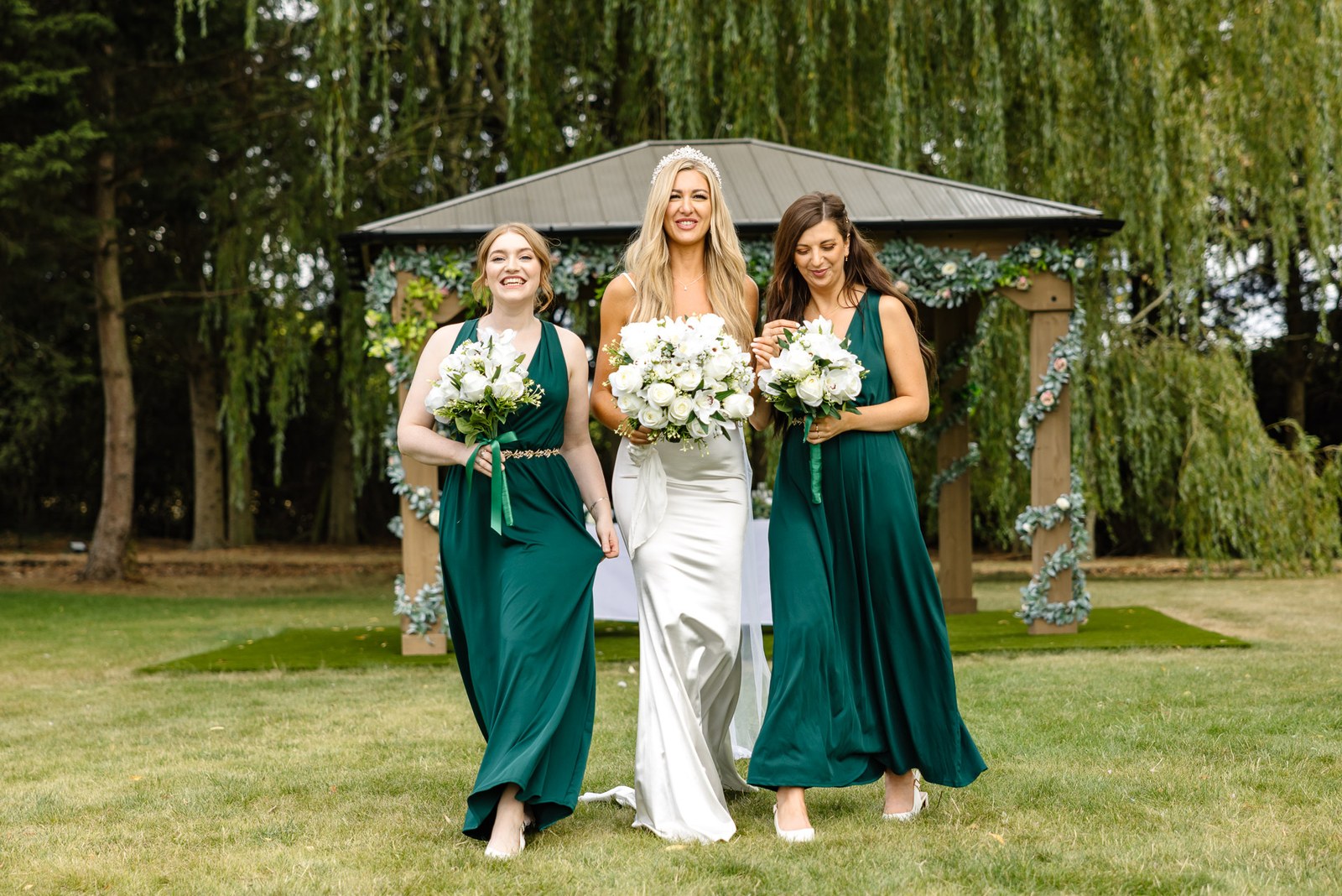 The bride with her two bridesmaids in green before the gazebo