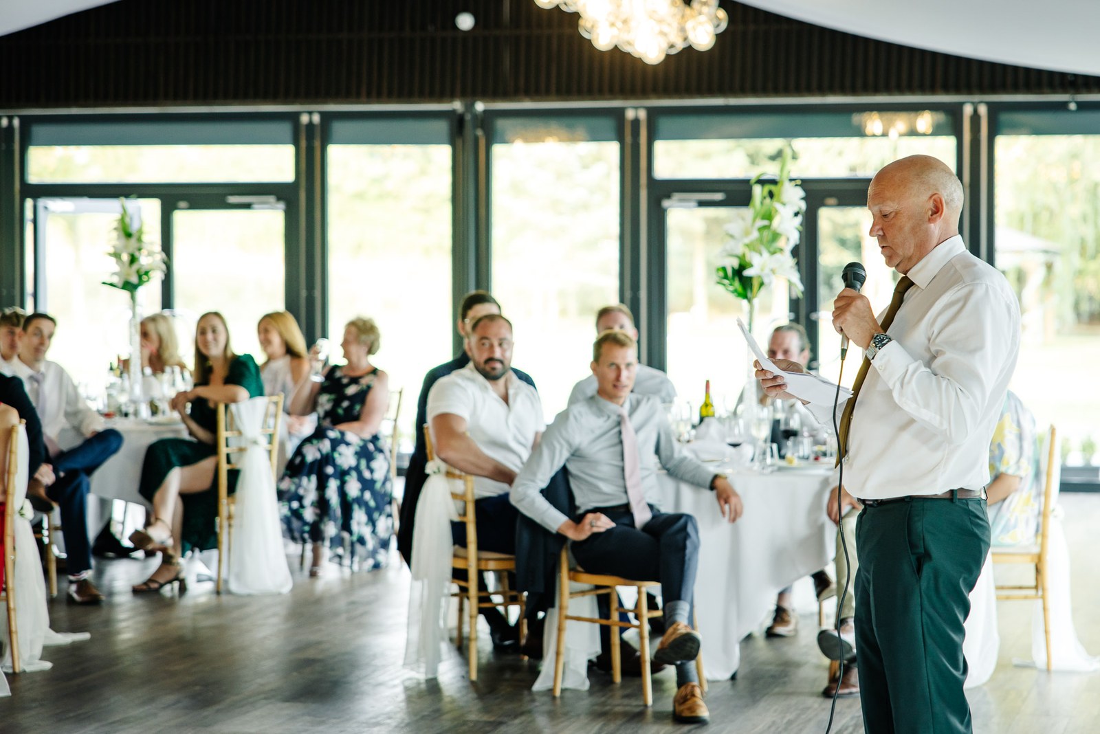 A guest giving a speech in the reception room as the seated guests listen