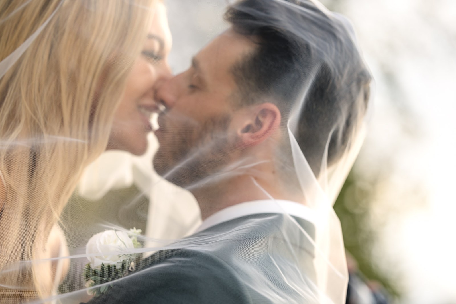 The couple kissing beneath the bride's veil, close up