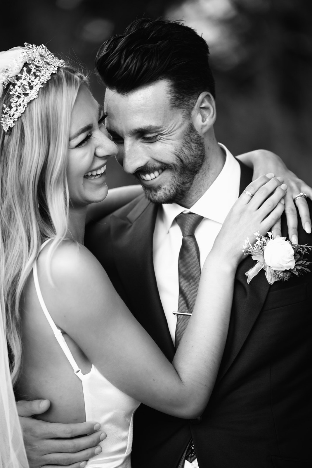 Black-and-white close portrait of the couple embracing, the bride in her jewelled tiara
