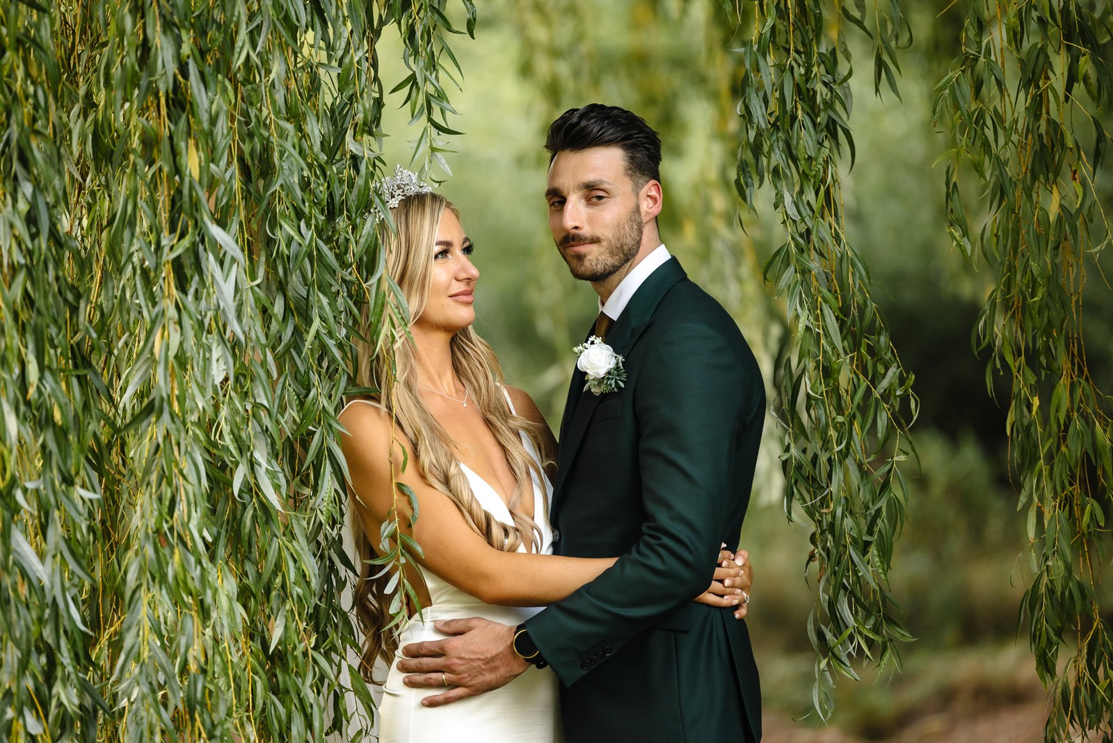 The couple embracing beneath a willow in the grounds of the Chesterton Hotel