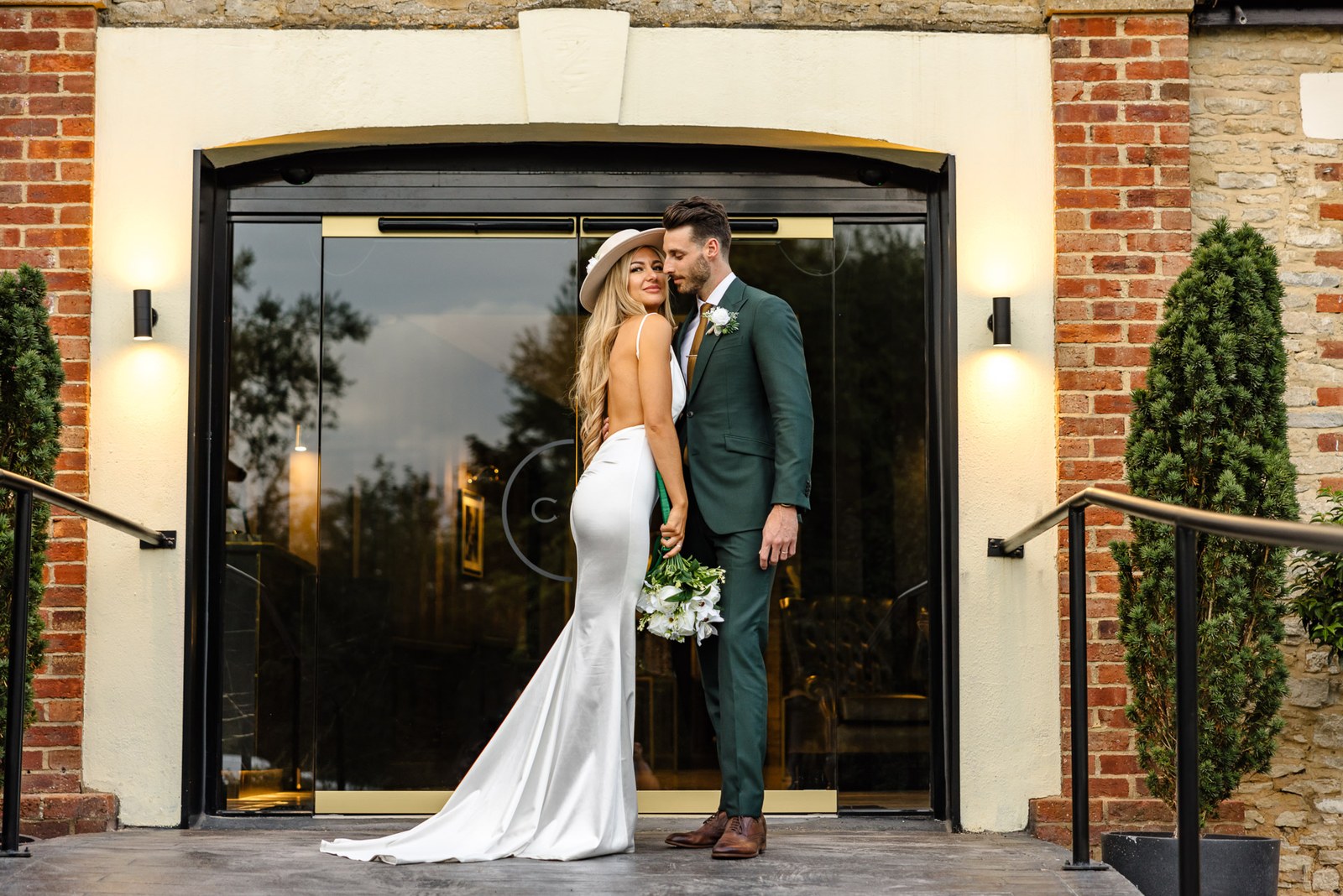 The couple kissing in the arched glass doorway of the Chesterton Hotel