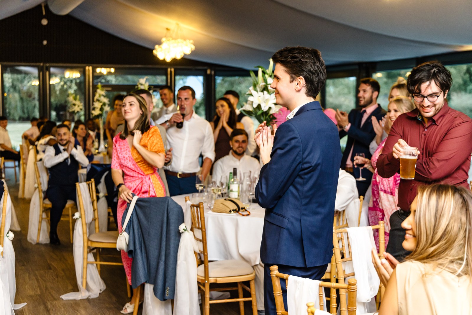 Guests rising to applaud in the chandelier-lit reception room