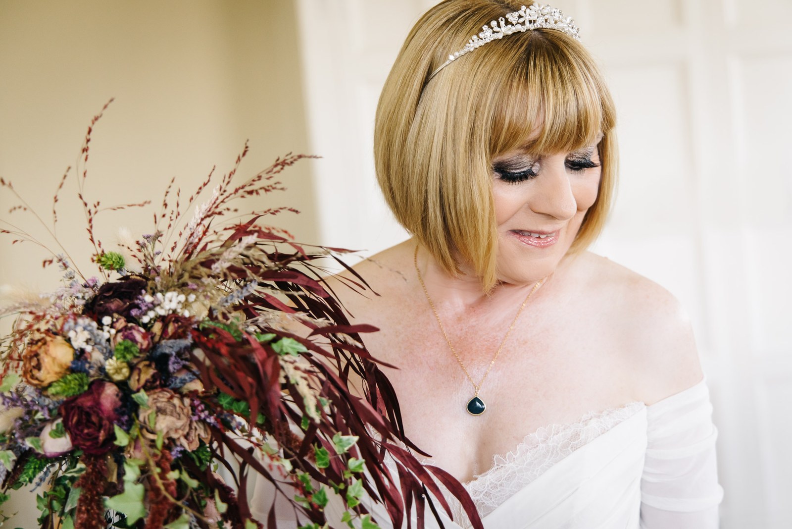 Bride holding a cascading burgundy bouquet, tiara catching the light