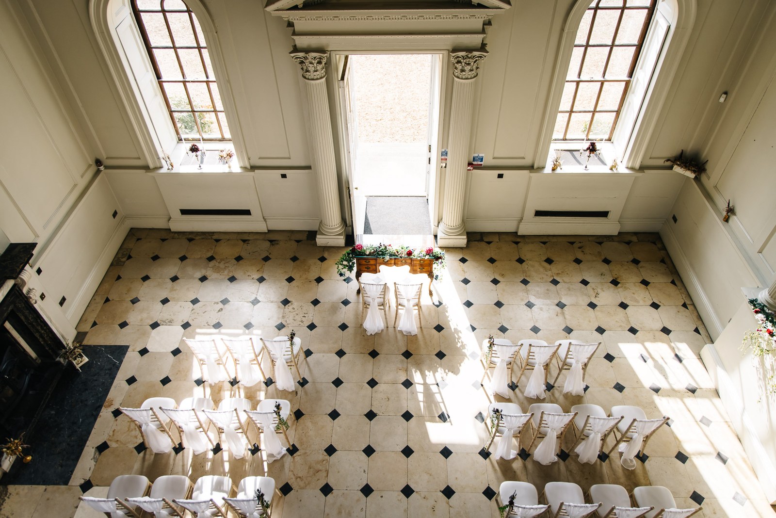 Elevated view of the ceremony room at Chicheley Hall, white chairs set on a tiled floor