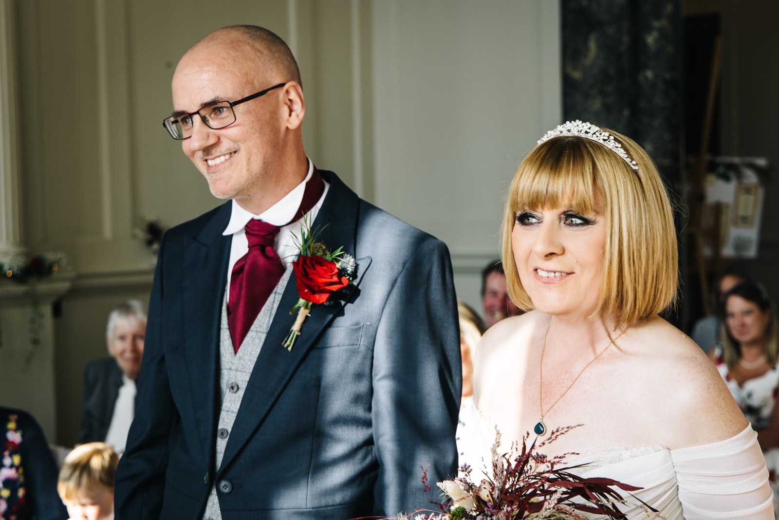 The couple stand together during the ceremony, the bride holding her bouquet