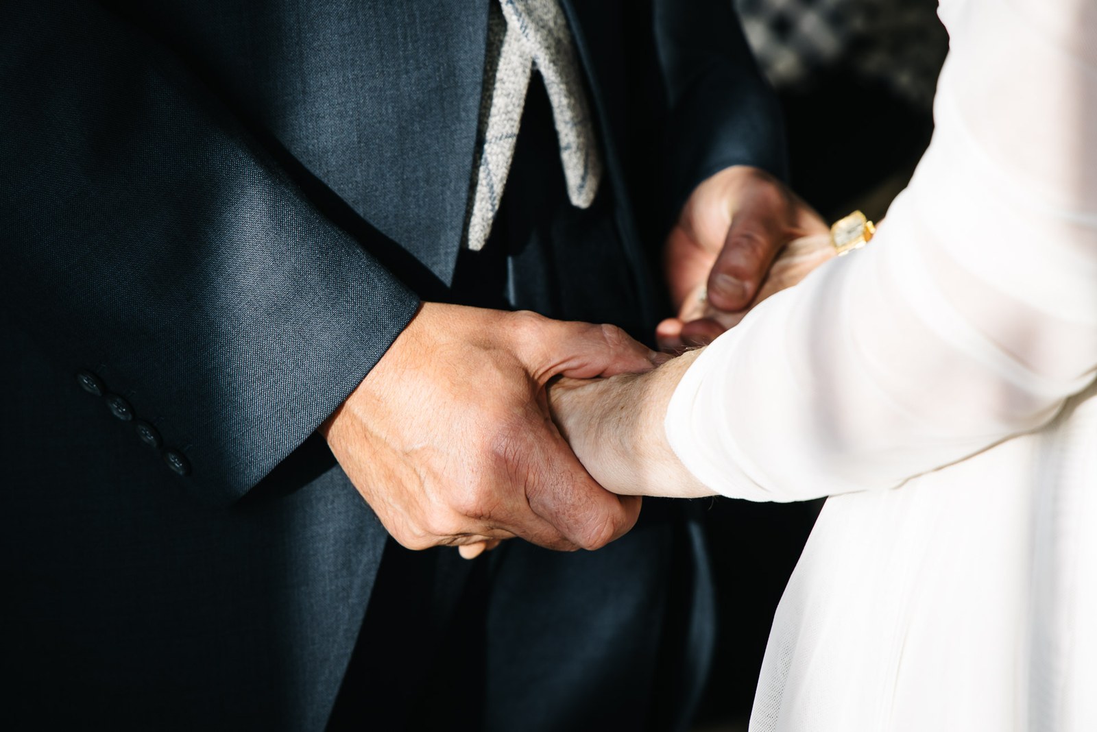 Close-up of the couple's hands clasped together during the ceremony