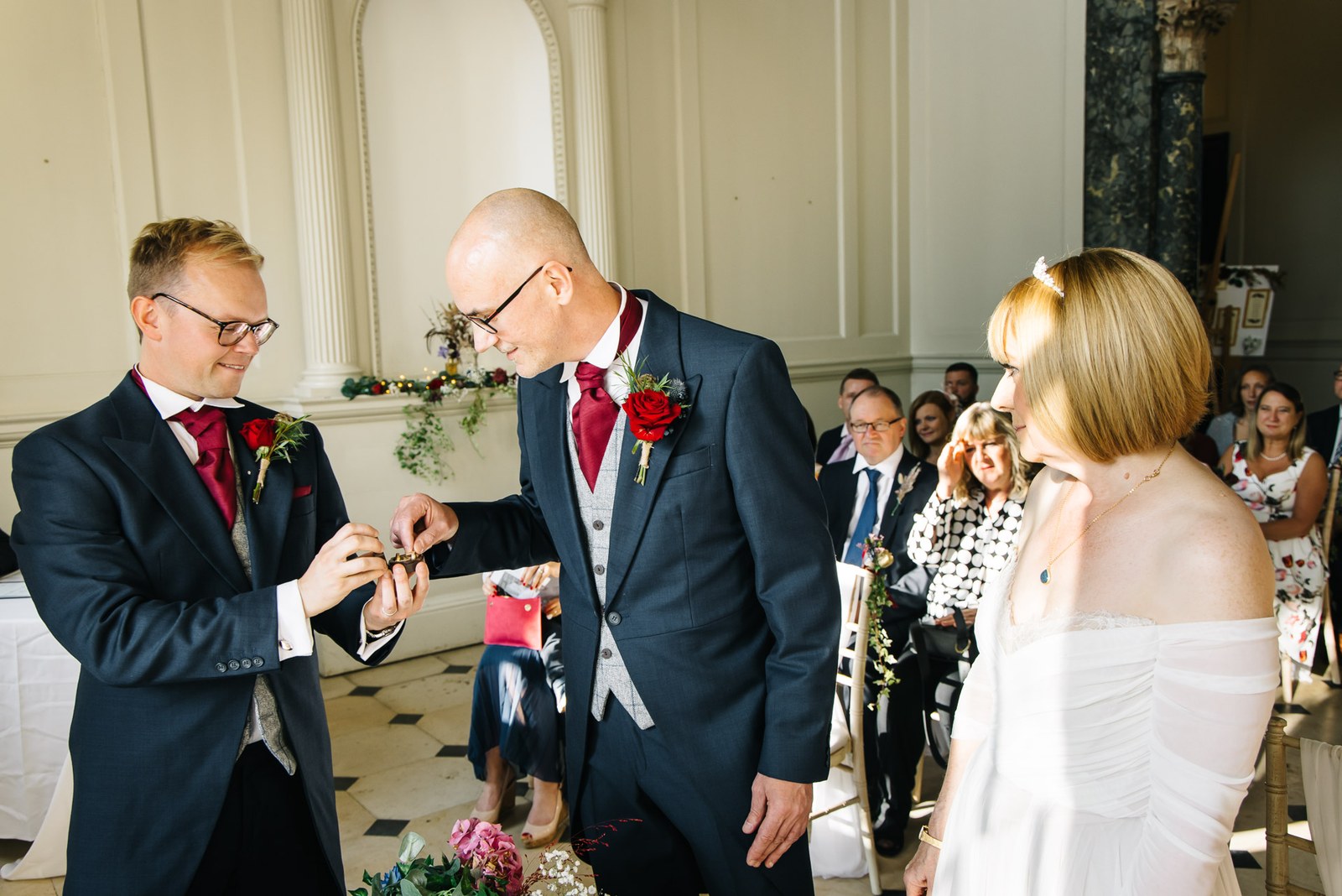 Groom being handed the ring as guests look on during the ceremony