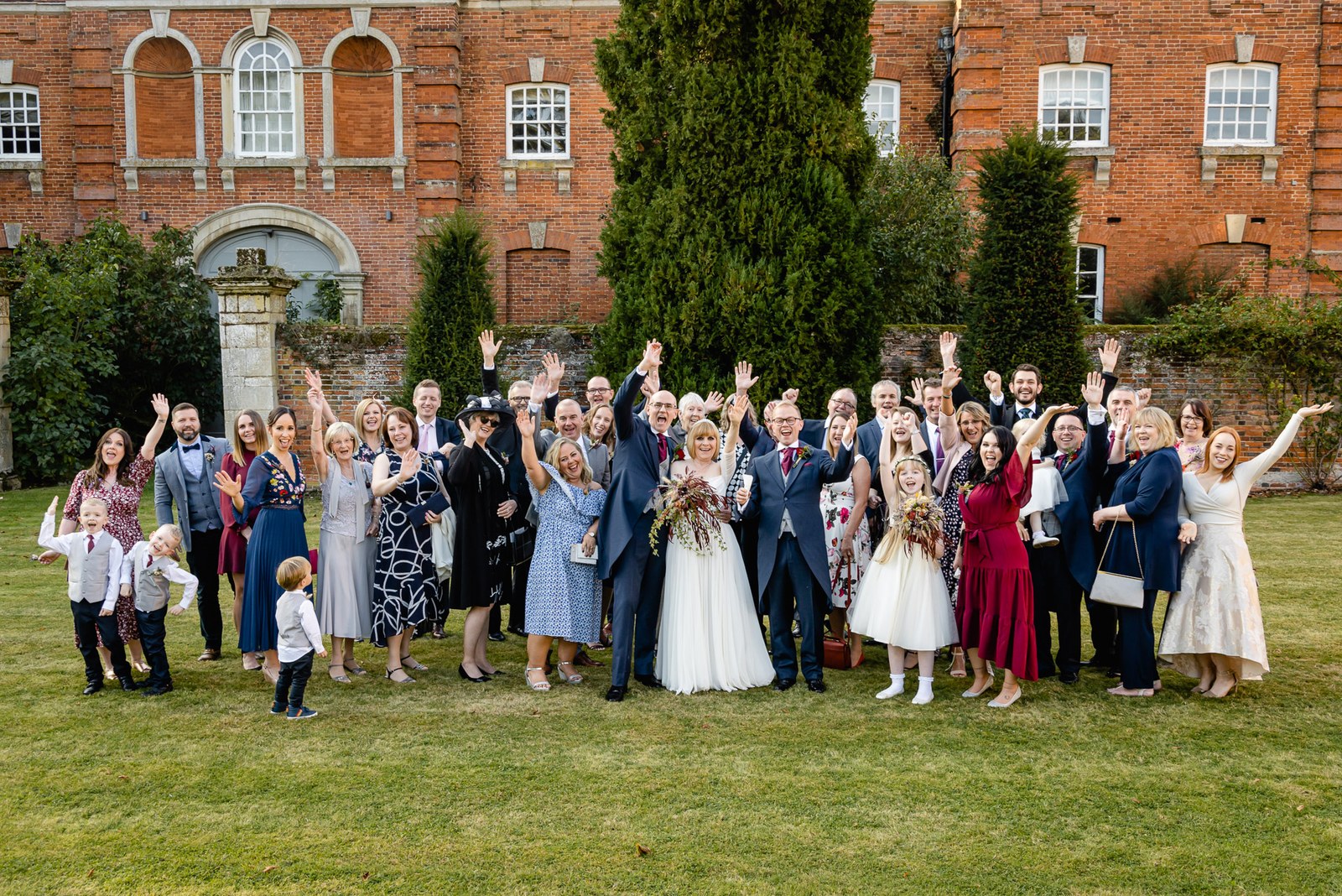 Wedding guests gathered for a group photograph on the lawn before Chicheley Hall