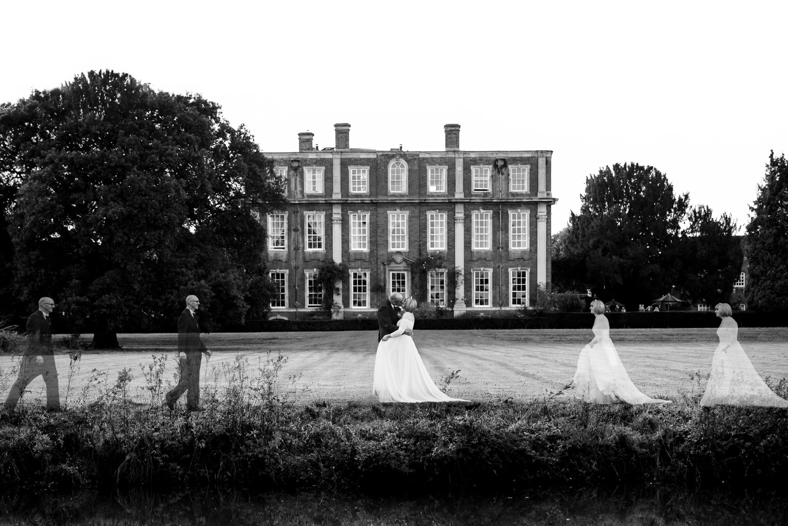 Black-and-white view of Chicheley Hall with the couple small on the sweeping lawn