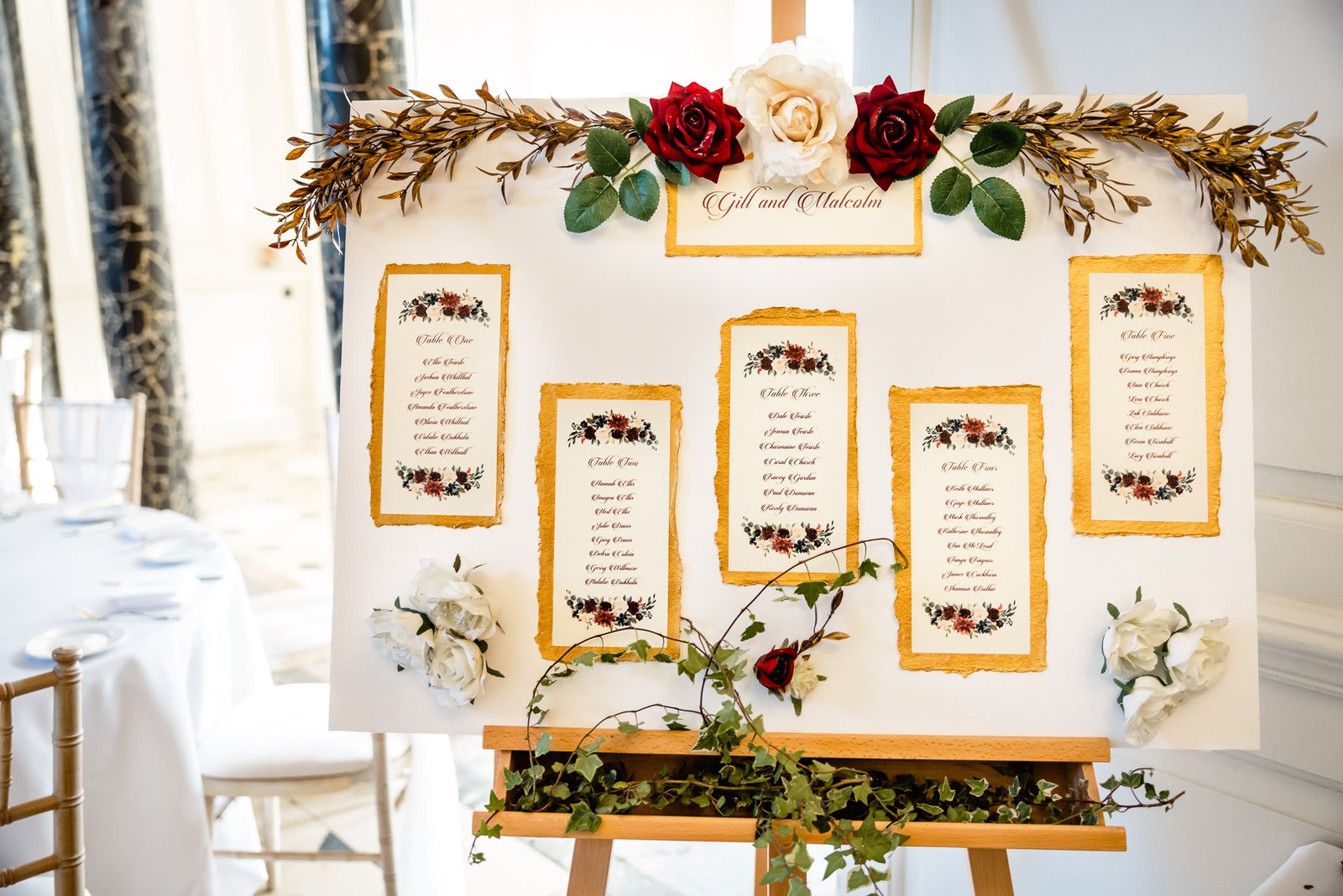 Floral table plan displayed on an easel, dressed with red and cream roses
