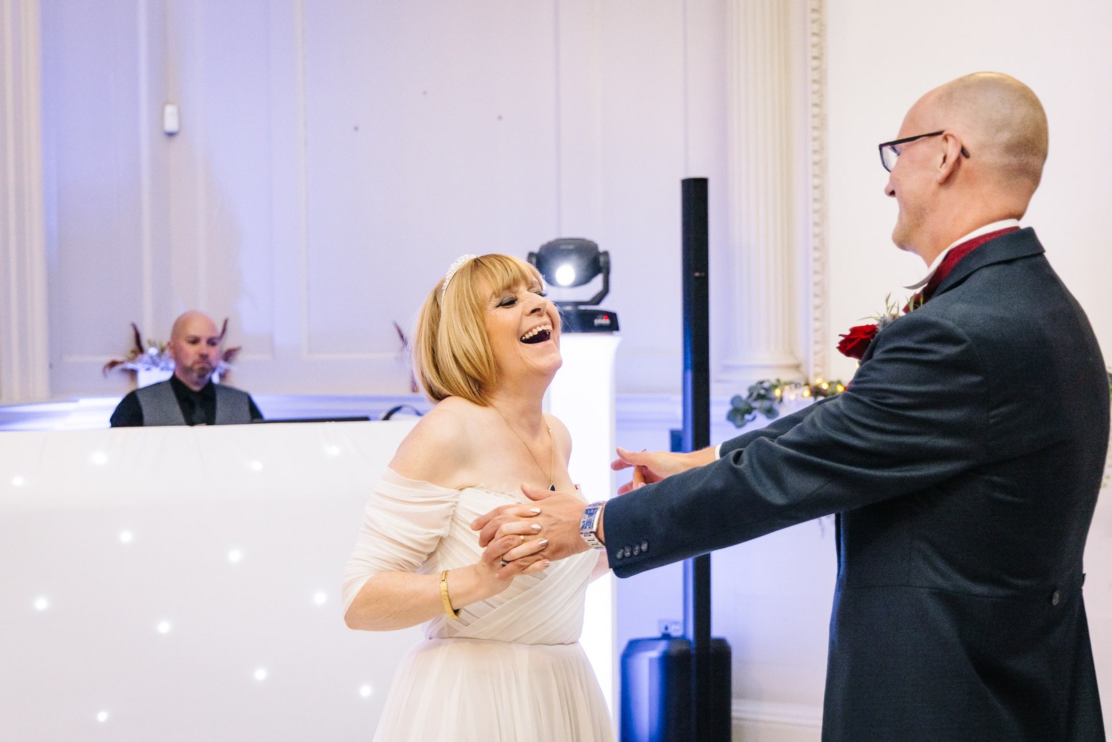 Bride and groom dance and laugh together in front of the DJ