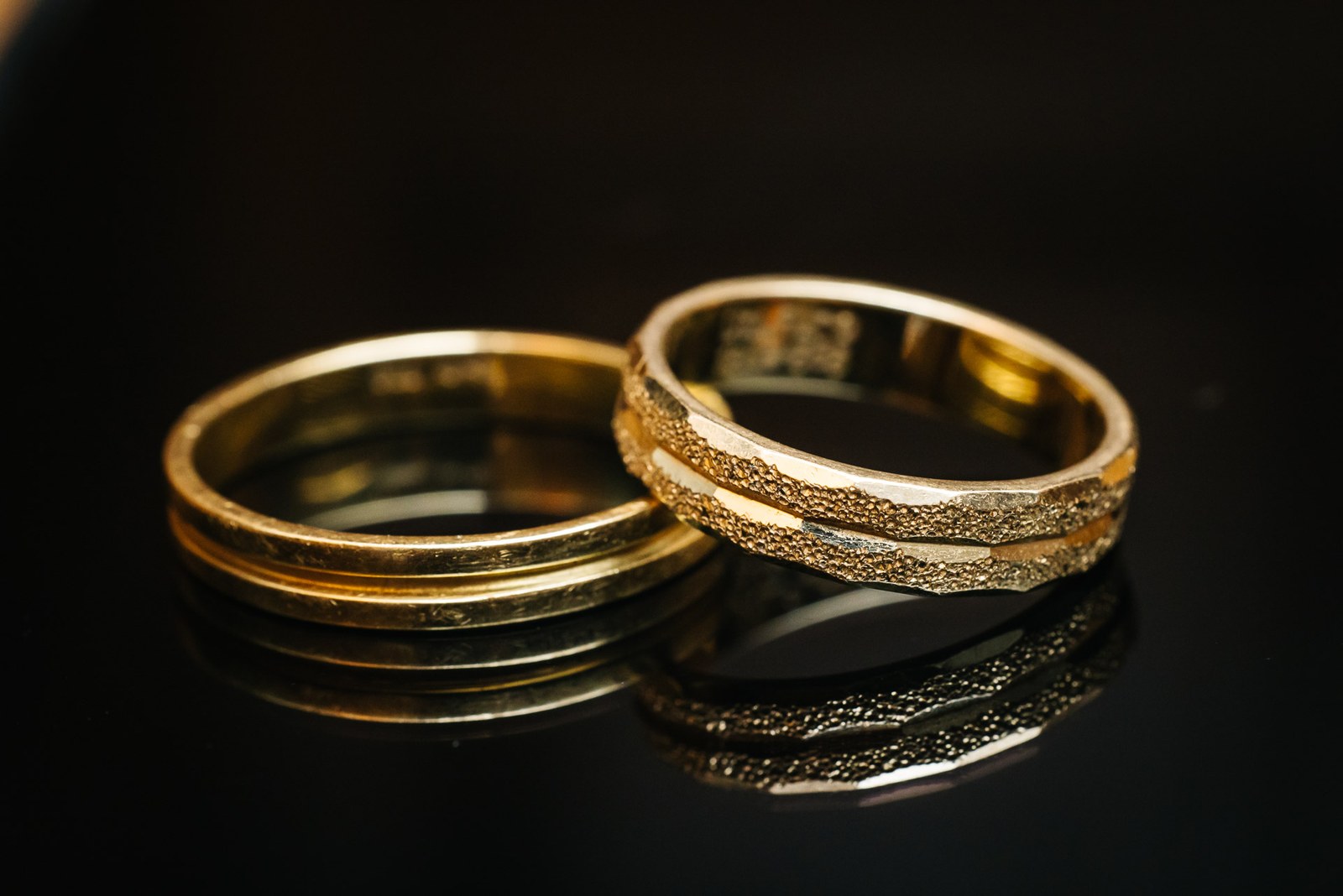 Close-up of the couple's two gold wedding rings on a dark surface