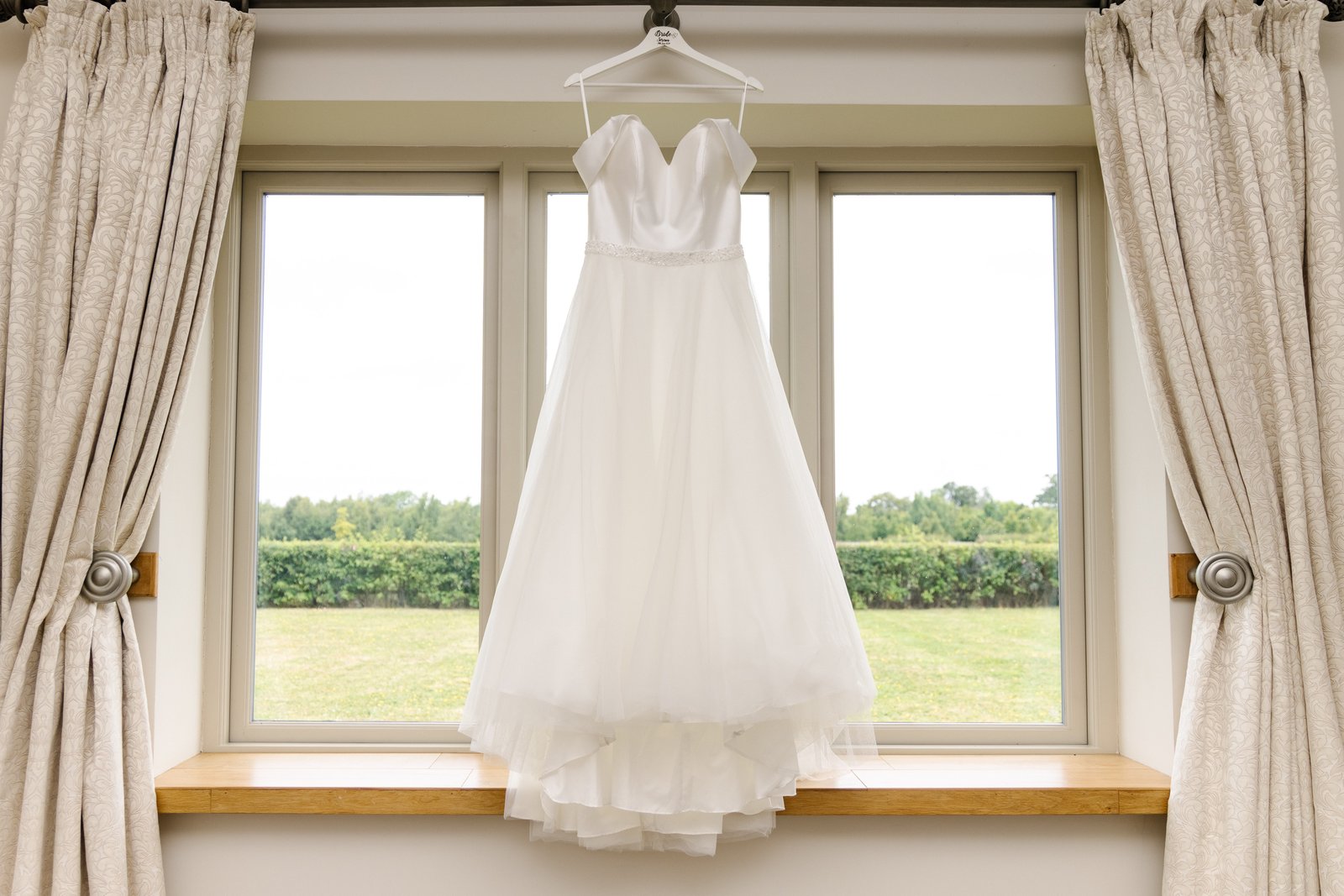 The wedding dress hanging in a window of the getting ready room at Cider Mill Barns