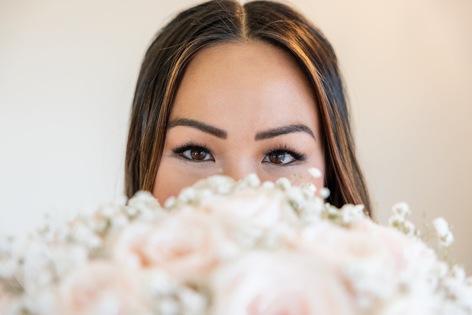 Close portrait of the bride looking over the top of her bouquet