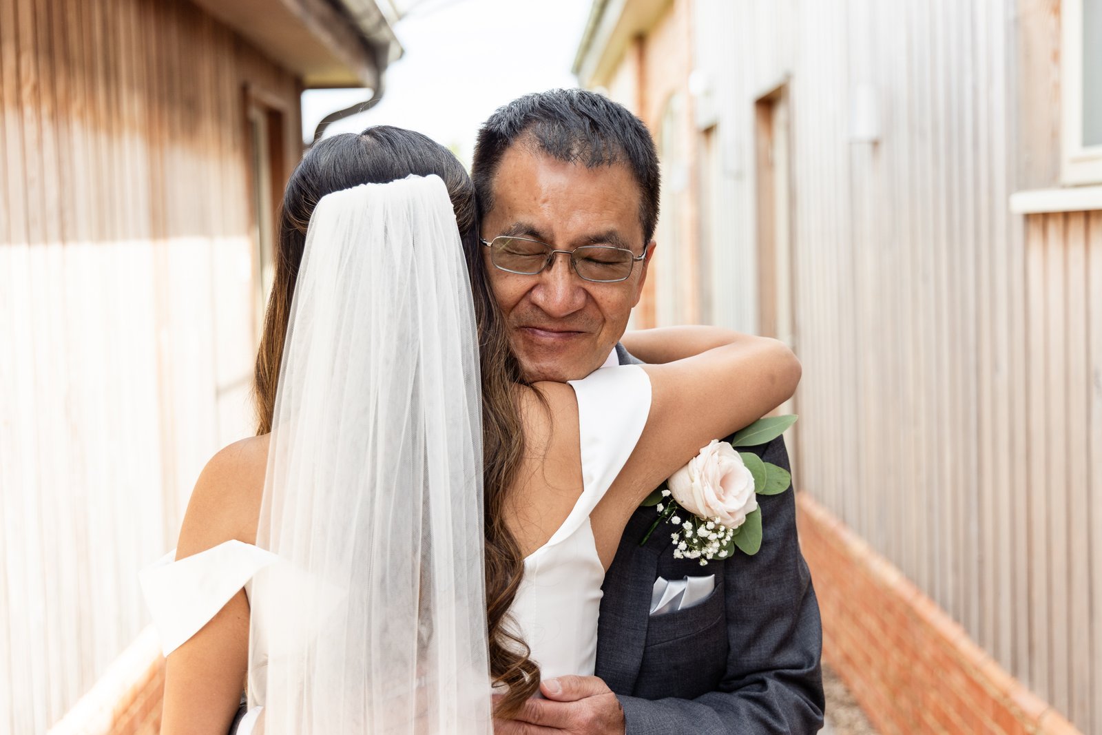 The bride hugging her father in the passage outside