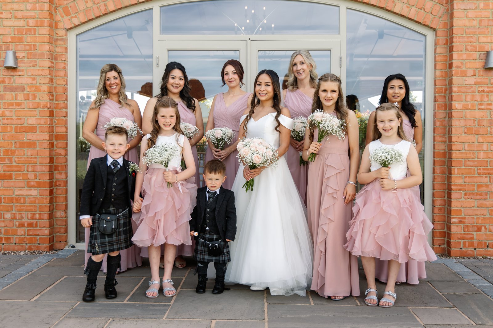 The bride with her bridesmaids and page boys by the glass doors at Cider Mill Barns