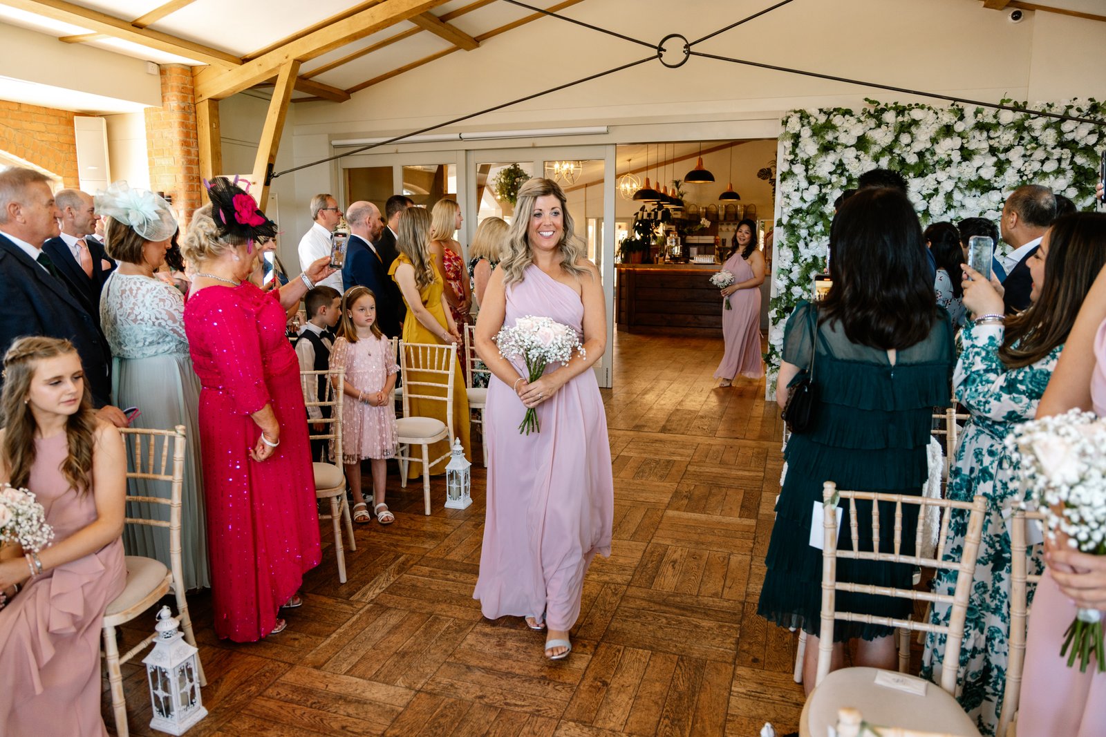 Bridesmaids walking down the aisle between seated guests