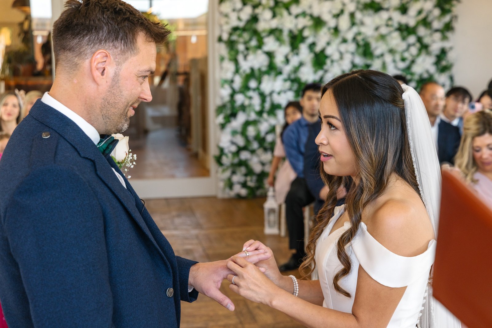 The couple holding hands in front of the flower arch during the ceremony