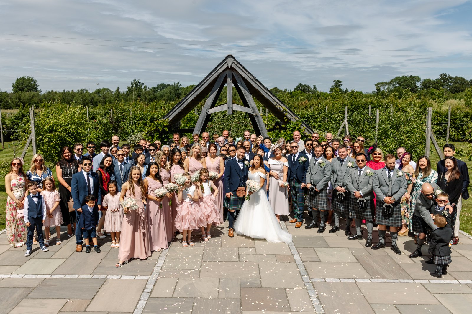 The whole wedding party on the terrace in front of the oak frame at Cider Mill Barns