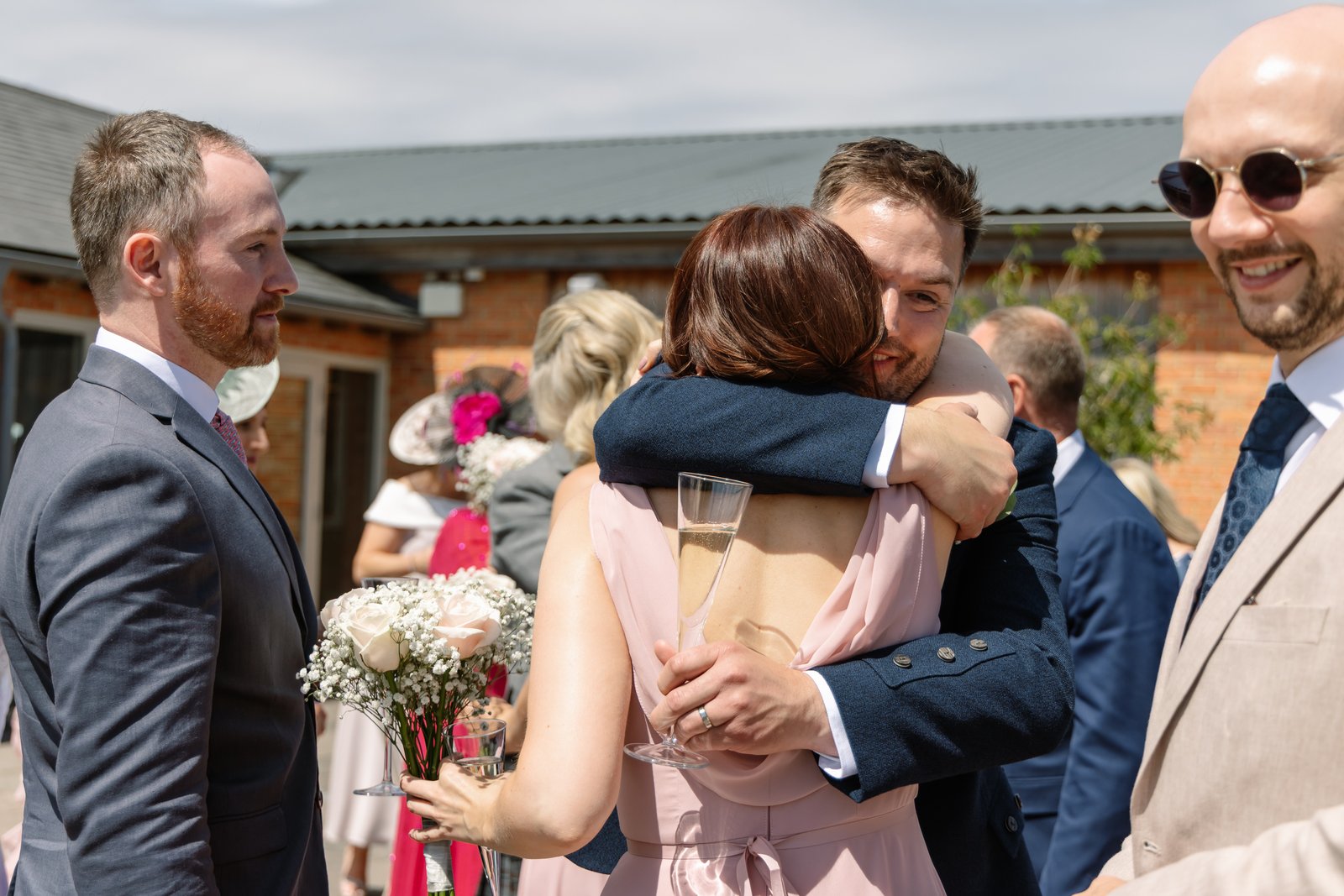 The groom hugging a guest outside during the drinks reception
