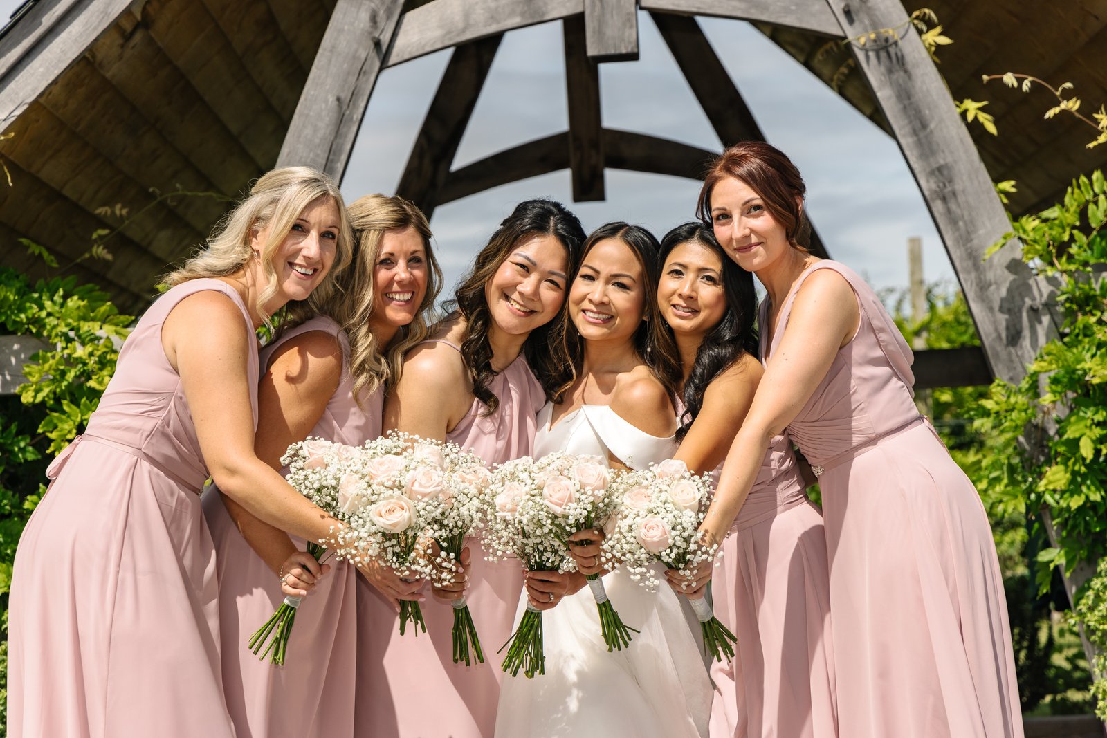 The bride and her bridesmaids leaning in together with their bouquets