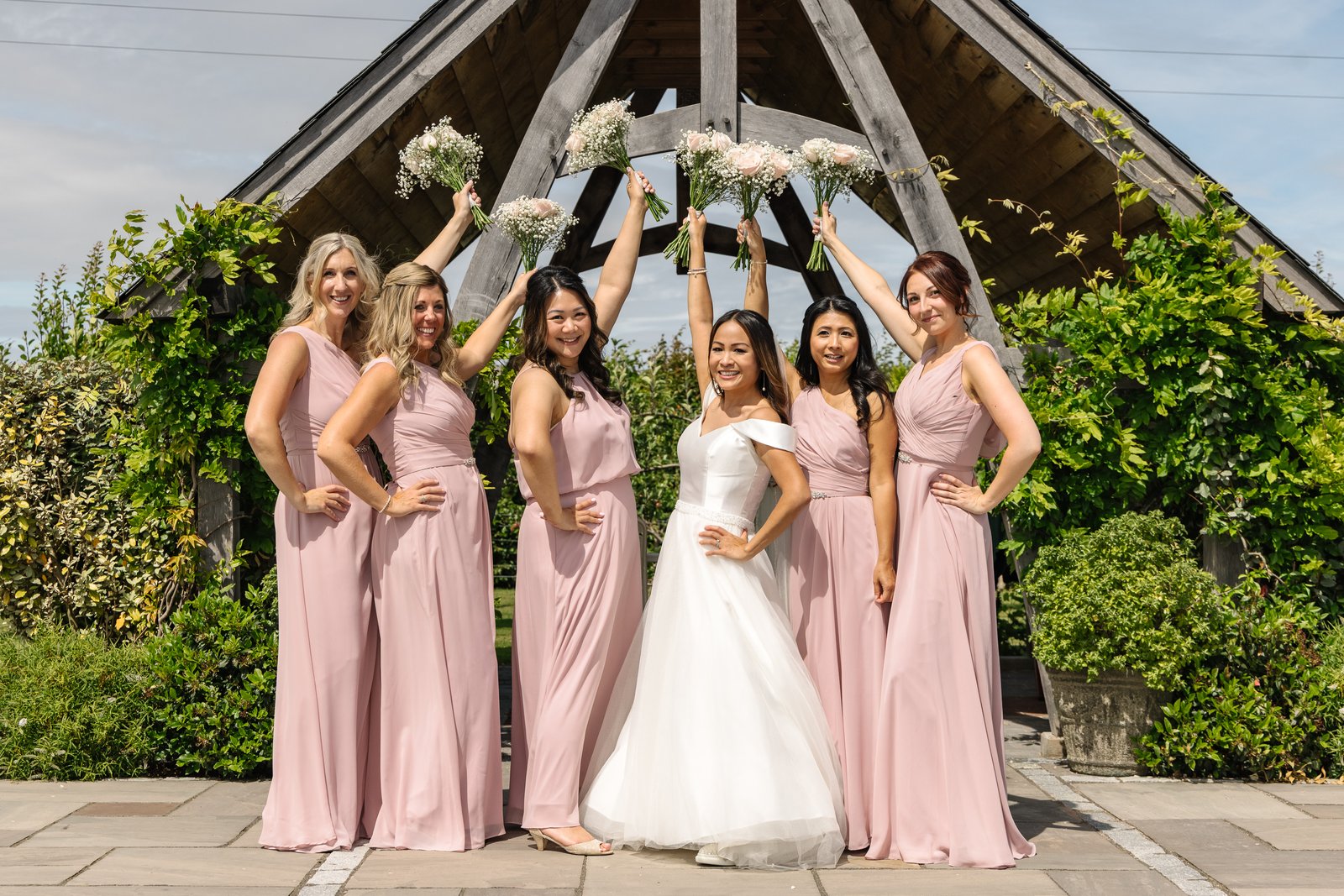 Bridesmaids holding their bouquets up in an arch over the bride